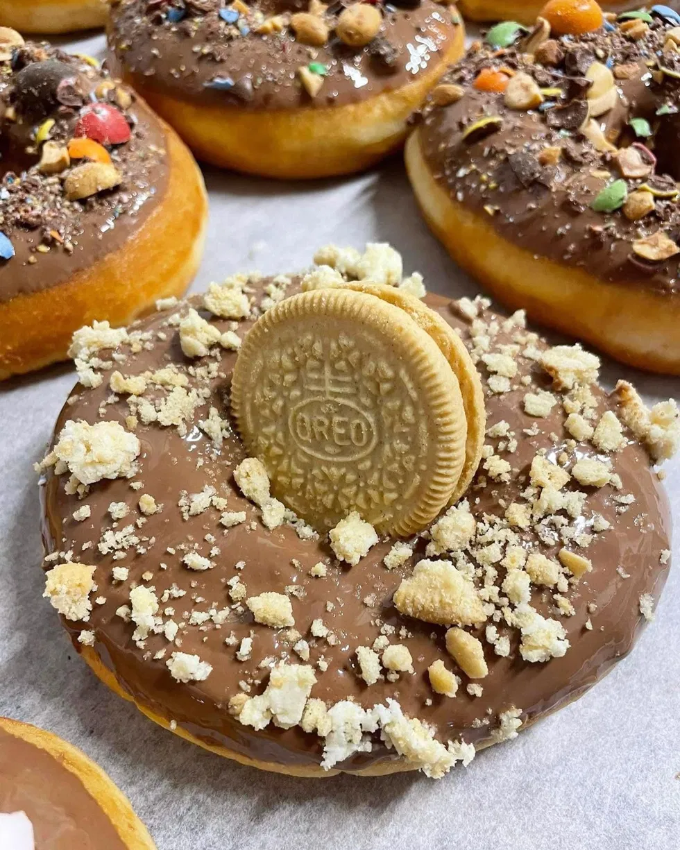 Donut au glaçage chocolat au lait avec éclats de biscuits et biscuit sandwich doré